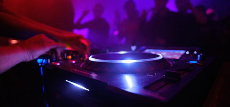 A closeup shot of DJ's equipment and the people dancing in the club