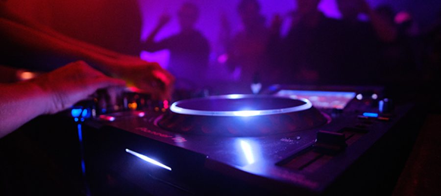 A closeup shot of DJ's equipment and the people dancing in the club