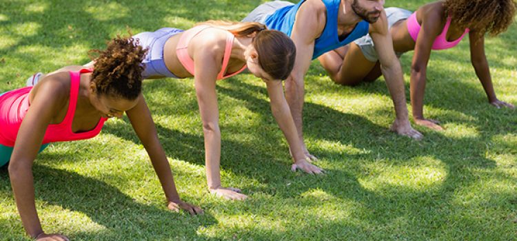 Group of friends doing push ups in park